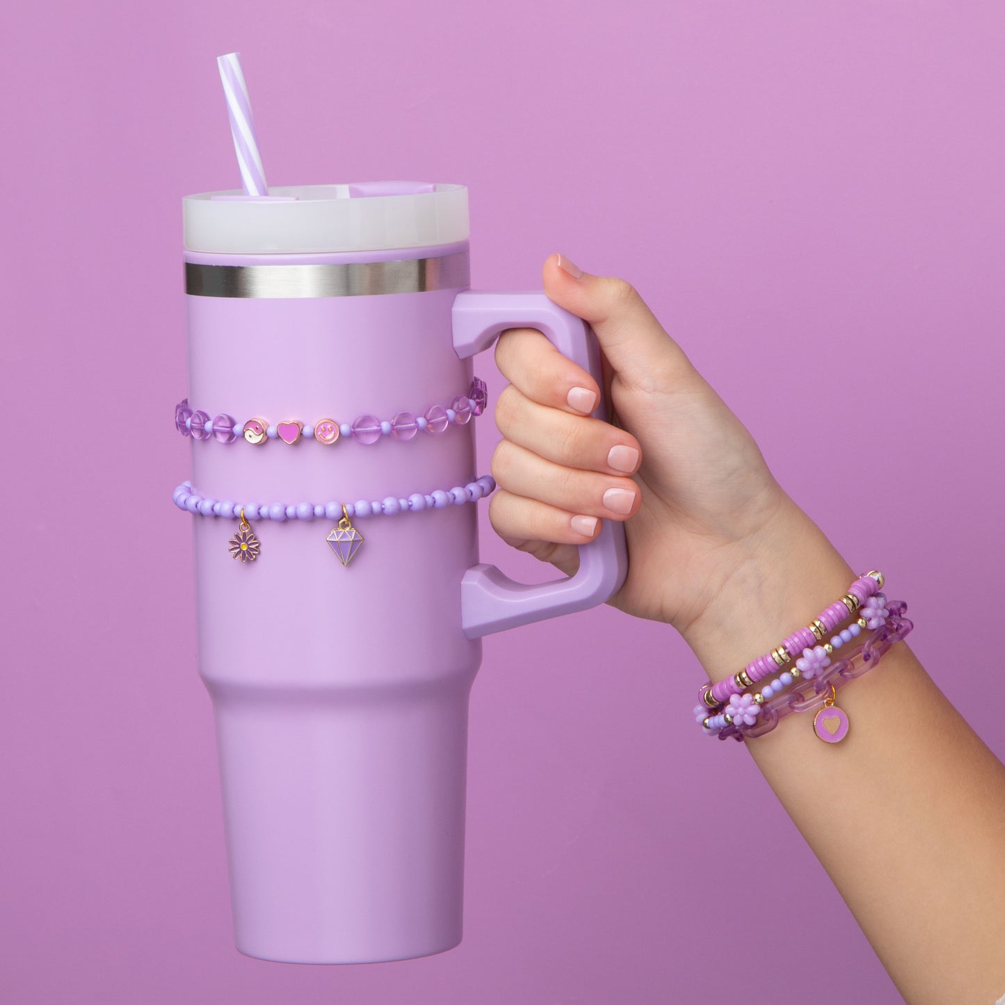 A braceleted hand holding a purple hydration cup with bracelets on the cup.