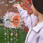Person holding a colorful string art sun and moon decoration outdoors.